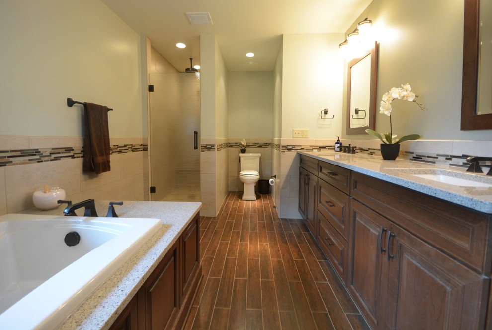Design ideas for a large traditional ensuite bathroom in Milwaukee with a submerged sink, raised-panel cabinets, dark wood cabinets, solid surface worktops, a built-in bath, an alcove shower, a two-piece toilet, green walls, porcelain flooring, porcelain tiles, brown floors, a hinged door and multi-coloured tiles.