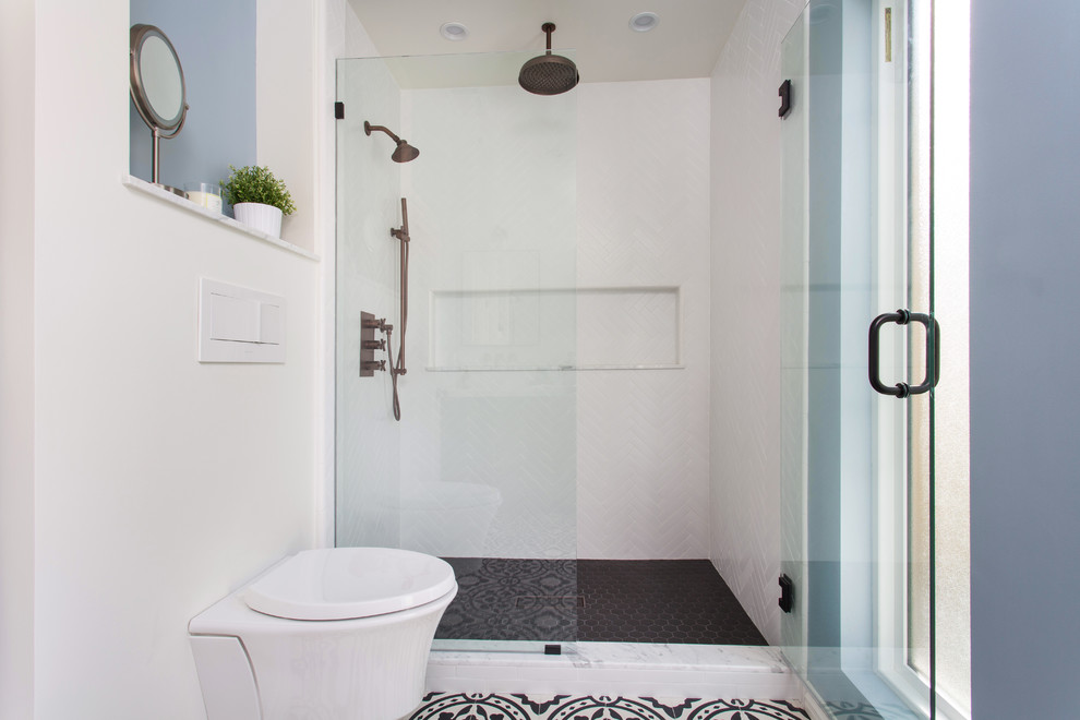Cette image montre une salle de bain nordique de taille moyenne avec un placard en trompe-l'oeil, des portes de placard noires, WC suspendus, un carrelage blanc, des carreaux de porcelaine, un mur gris, carreaux de ciment au sol, un lavabo encastré, un plan de toilette en marbre, un sol noir et une cabine de douche à porte battante.