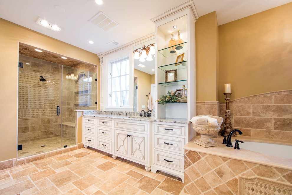 Стильный дизайн: большая главная ванная комната в классическом стиле с фасадами с декоративным кантом, искусственно-состаренными фасадами, полновстраиваемой ванной, угловым душем, каменной плиткой, желтыми стенами и врезной раковиной - последний тренд