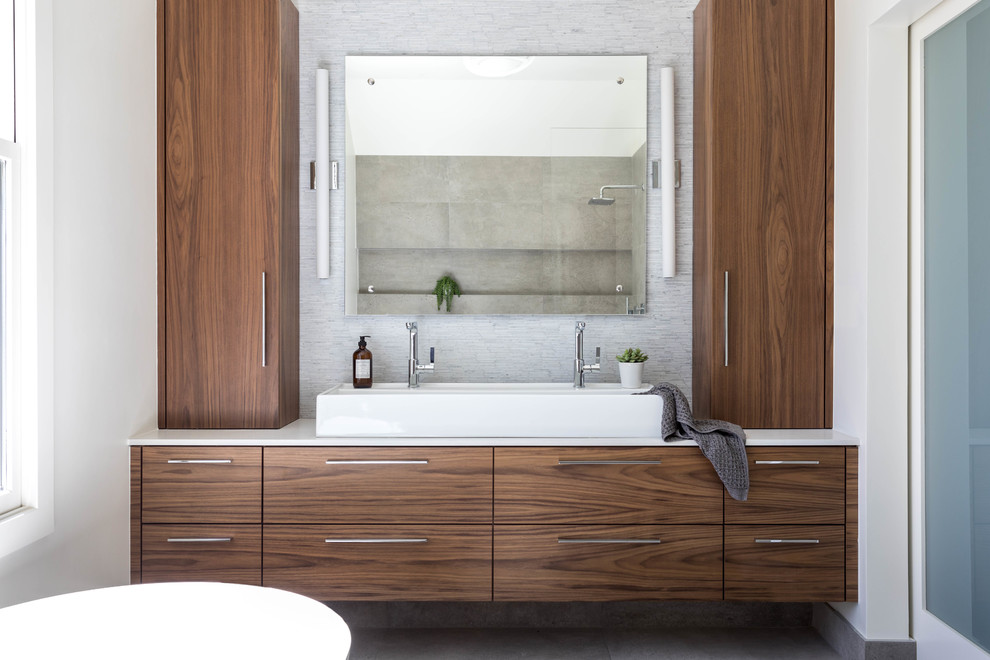Diseño de cuarto de baño principal contemporáneo con armarios con paneles lisos, puertas de armario de madera en tonos medios, paredes blancas, lavabo sobreencimera y suelo gris