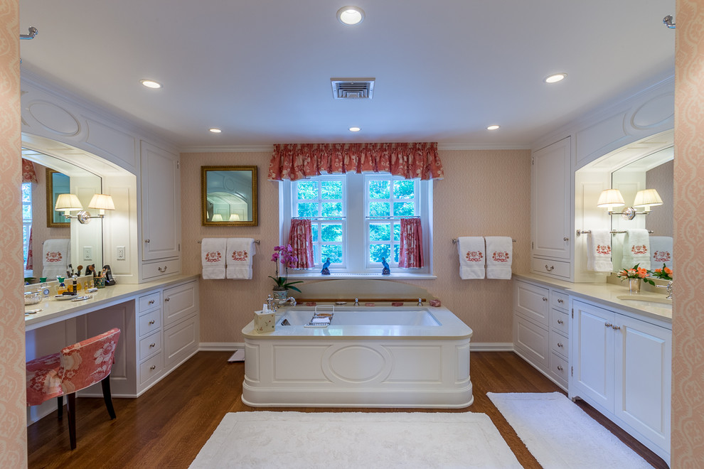 Bild på ett stort vintage en-suite badrum, med ett integrerad handfat, luckor med upphöjd panel, vita skåp, en jacuzzi, rosa väggar och mellanmörkt trägolv