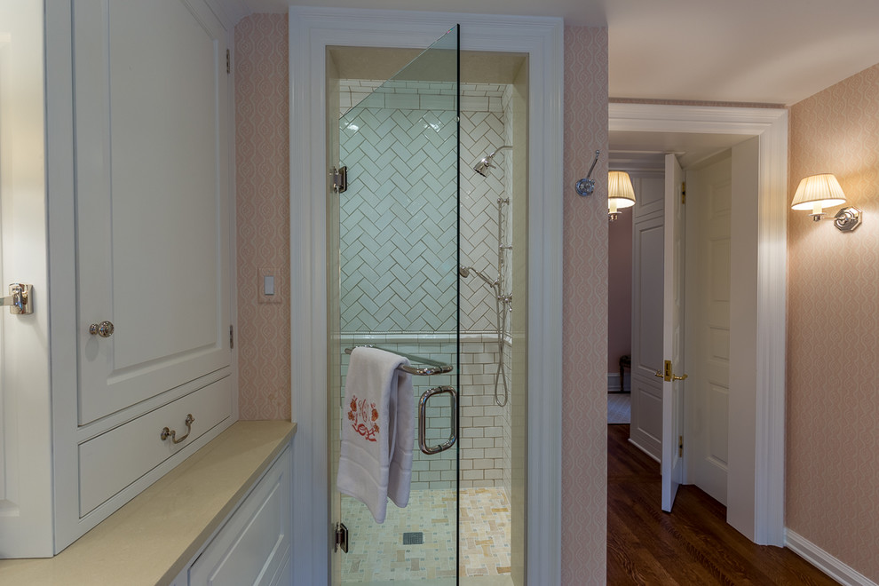 Aménagement d'une grande salle de bain principale classique avec un lavabo intégré, un placard avec porte à panneau surélevé, des portes de placard blanches, un mur rose et un sol en bois brun.