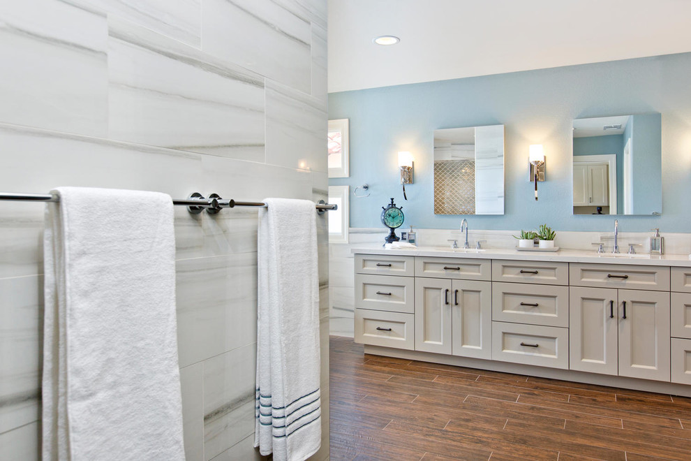 Photo of a large traditional ensuite bathroom in Denver with recessed-panel cabinets, white cabinets, a freestanding bath, a walk-in shower, a wall mounted toilet, yellow tiles, porcelain tiles, blue walls, porcelain flooring, a submerged sink and engineered stone worktops.