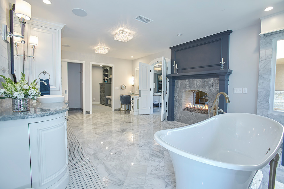 Inspiration pour une grande salle de bain principale design avec un placard avec porte à panneau surélevé, des portes de placard blanches, une baignoire indépendante, un mur gris, un sol en marbre, une vasque, un plan de toilette en granite et un sol gris.