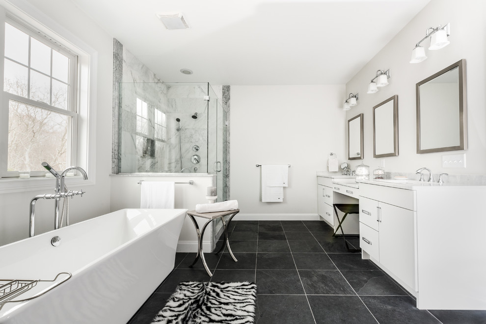 Expansive modern ensuite bathroom in Providence with flat-panel cabinets, white cabinets, a freestanding bath, a corner shower, a two-piece toilet, white tiles, porcelain tiles, grey walls, slate flooring, a submerged sink and marble worktops.