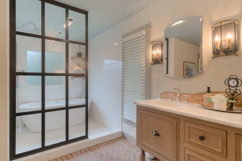Bild på ett mellanstort vintage en-suite badrum, med luckor med infälld panel, skåp i ljust trä, ett fristående badkar, en dusch/badkar-kombination, en toalettstol med hel cisternkåpa, vita väggar, tegelgolv och ett undermonterad handfat