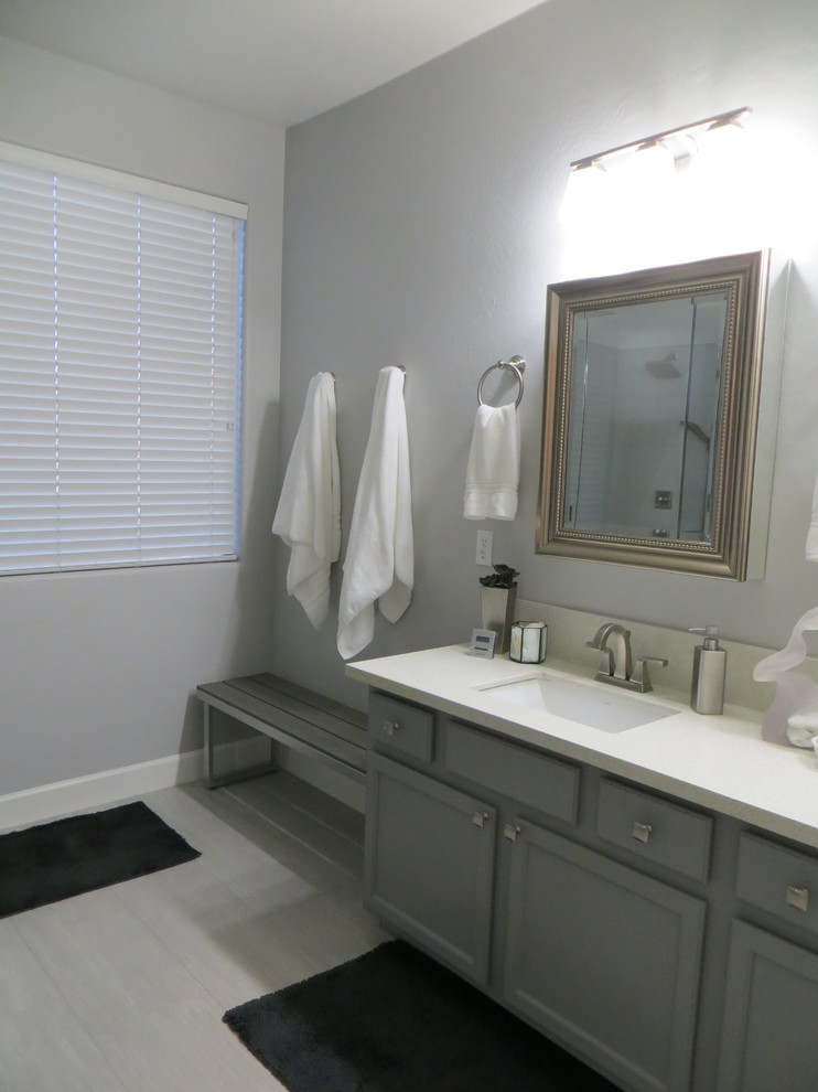 Cette photo montre une salle de bain principale tendance de taille moyenne avec un placard avec porte à panneau encastré, des portes de placard grises, une douche d'angle, WC séparés, un carrelage gris, des carreaux de porcelaine, un mur gris, un sol en carrelage de porcelaine, un lavabo encastré et un plan de toilette en quartz modifié.