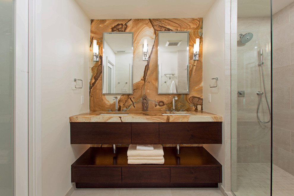 Cette image montre une douche en alcôve principale design en bois foncé de taille moyenne avec un lavabo encastré, un placard à porte plane, un carrelage beige, des carreaux de porcelaine, un mur gris, un sol en carrelage de porcelaine et un plan de toilette en onyx.