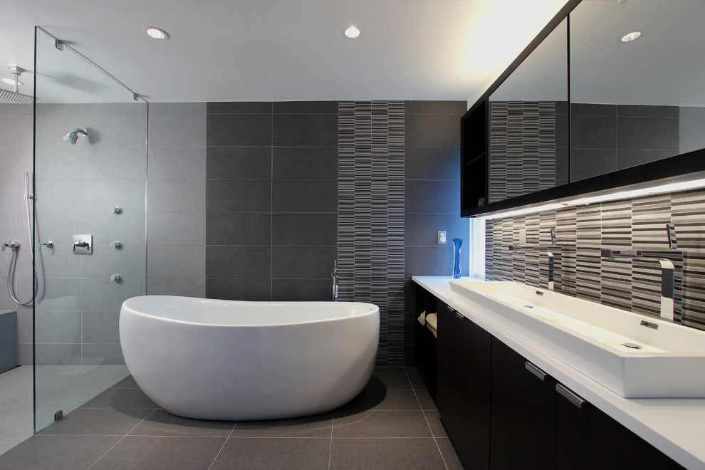 Ejemplo de cuarto de baño gris y negro contemporáneo con armarios con paneles lisos, puertas de armario de madera en tonos medios, bañera exenta y ducha a ras de suelo