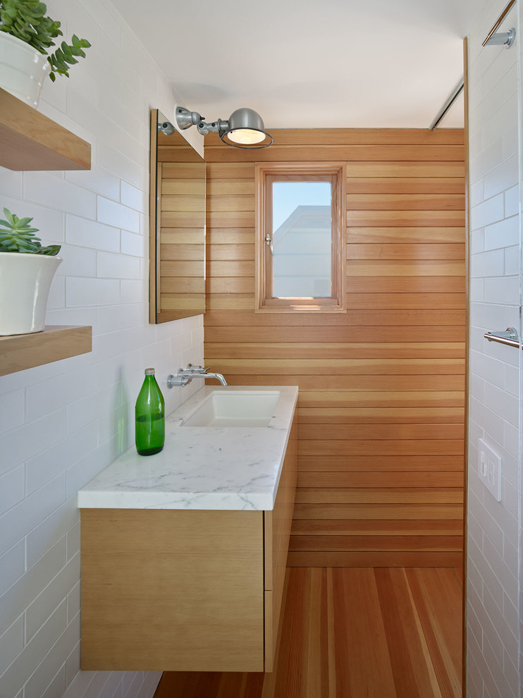 Inspiration för mellanstora moderna en-suite badrum, med ett undermonterad handfat, släta luckor, skåp i mellenmörkt trä, bänkskiva i kalksten, vit kakel, tunnelbanekakel och mellanmörkt trägolv
