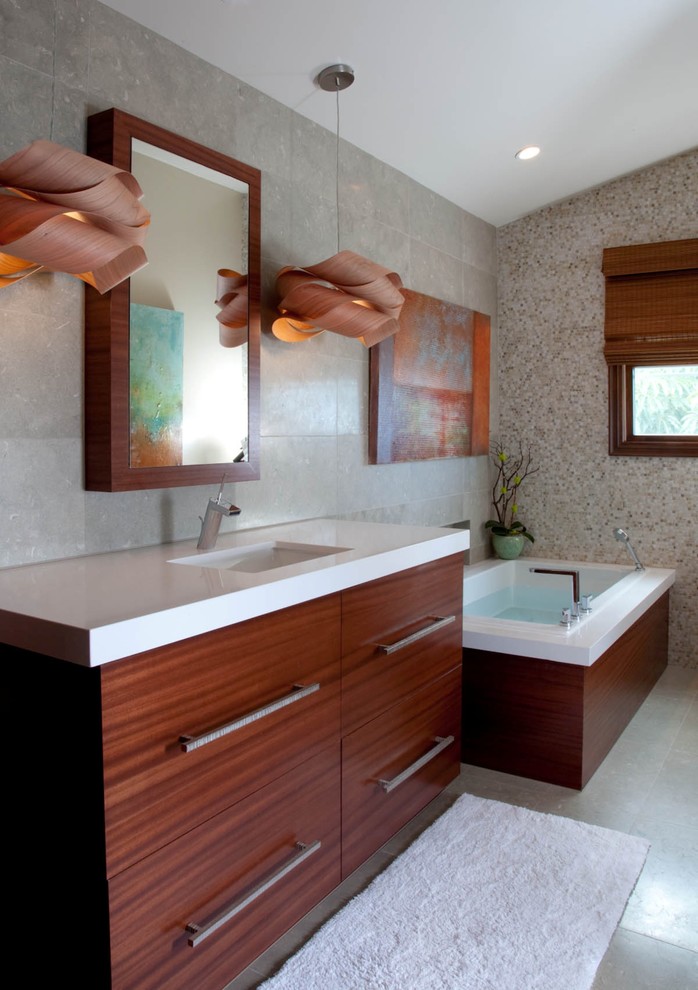 Imagen de cuarto de baño actual con lavabo bajoencimera, armarios con paneles lisos, puertas de armario de madera en tonos medios, bañera esquinera y baldosas y/o azulejos grises