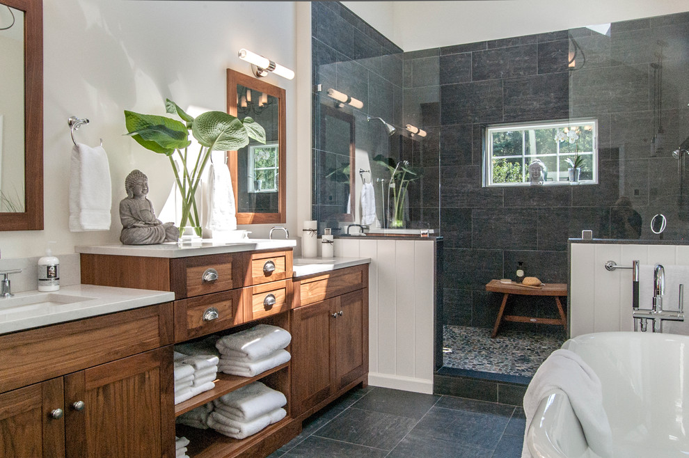 Inspiration for a large modern ensuite bathroom in Philadelphia with a submerged sink, medium wood cabinets, engineered stone worktops, a freestanding bath, a walk-in shower, a two-piece toilet, black tiles, porcelain tiles, beige walls, pebble tile flooring and shaker cabinets.