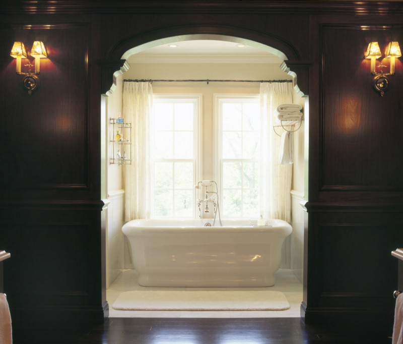 Idées déco pour une salle de bain principale classique avec un plan de toilette en marbre, une baignoire indépendante, un mur marron et parquet foncé.