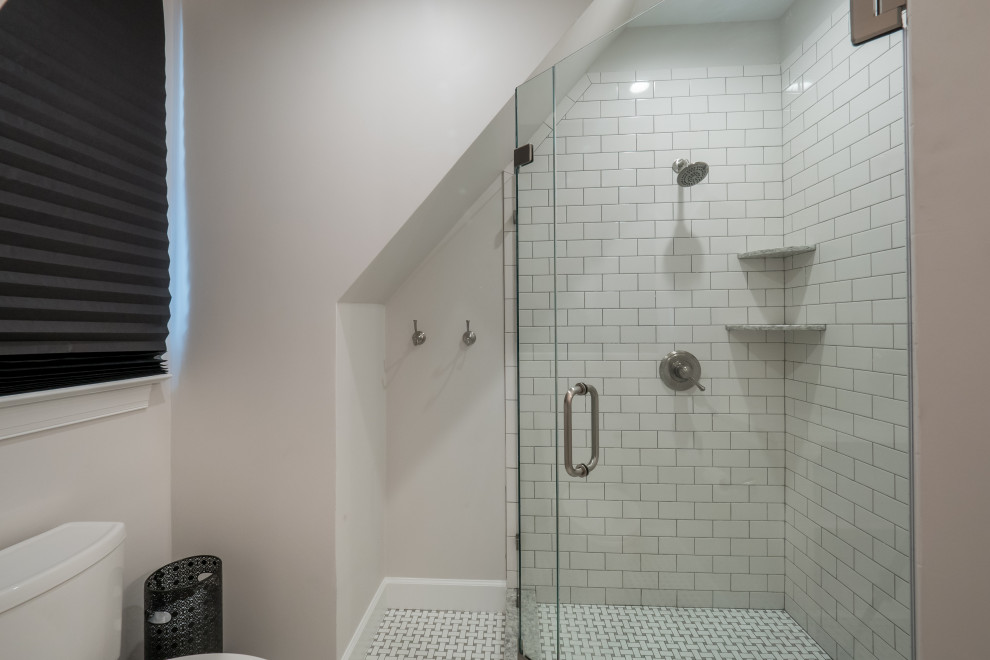 Cette image montre une salle d'eau traditionnelle de taille moyenne avec un placard avec porte à panneau encastré, des portes de placard blanches, une baignoire indépendante, une douche d'angle, WC à poser, un carrelage blanc, un carrelage métro, un mur gris, un sol en carrelage de céramique, un lavabo encastré, un plan de toilette en quartz modifié, un sol gris, une cabine de douche à porte battante et un plan de toilette blanc.