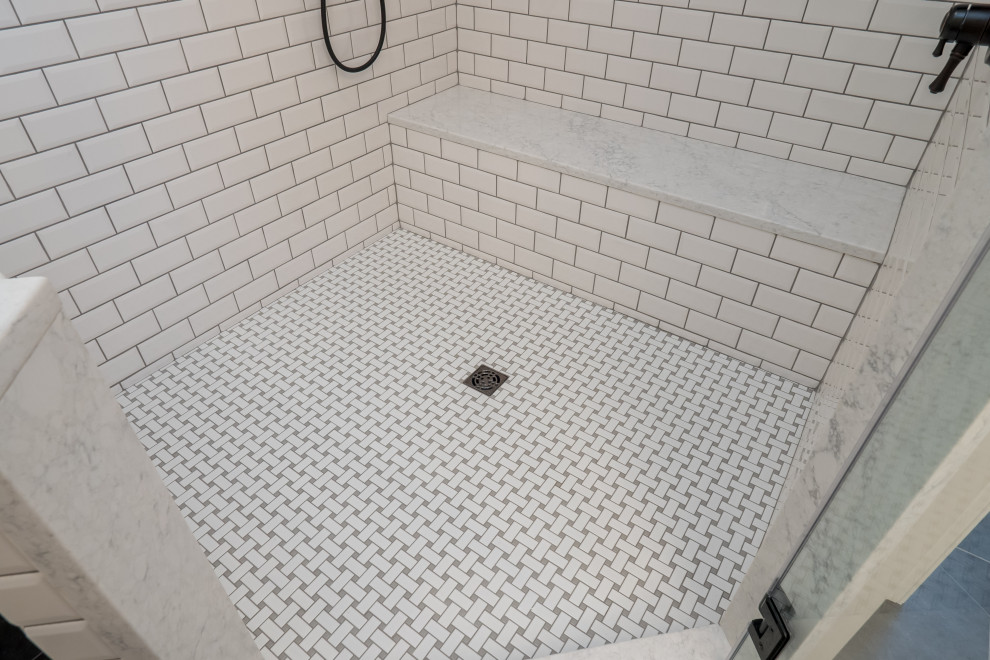 Cette photo montre une salle de bain principale chic de taille moyenne avec un placard avec porte à panneau encastré, des portes de placard blanches, une baignoire indépendante, une douche d'angle, WC à poser, un carrelage blanc, un carrelage métro, un mur gris, un sol en carrelage de céramique, un lavabo encastré, un plan de toilette en quartz modifié, un sol gris, une cabine de douche à porte battante et un plan de toilette blanc.