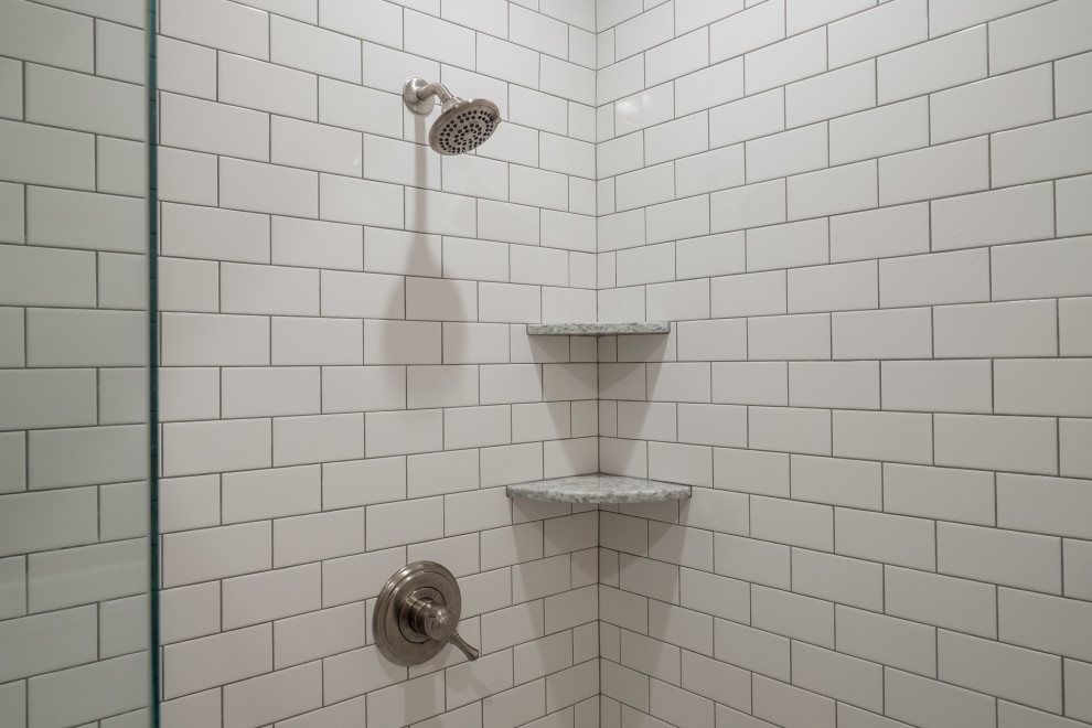 Klassisk inredning av ett mellanstort vit vitt badrum med dusch, med luckor med infälld panel, vita skåp, ett fristående badkar, en hörndusch, en toalettstol med hel cisternkåpa, vit kakel, tunnelbanekakel, grå väggar, klinkergolv i keramik, ett undermonterad handfat, bänkskiva i kvarts, grått golv och dusch med gångjärnsdörr