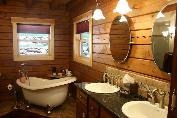 Inspiration for a rustic ensuite bathroom in Denver with a built-in sink, raised-panel cabinets, medium wood cabinets, granite worktops, a freestanding bath, beige tiles, stone tiles and travertine flooring.