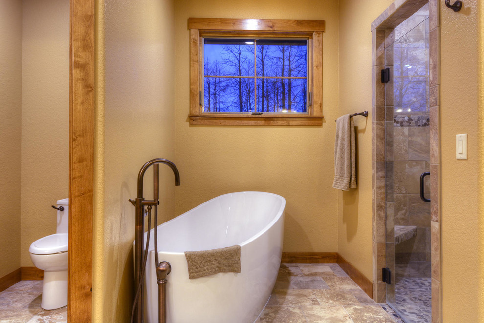 Rustik inredning av ett en-suite badrum, med ett fristående badkar, en dubbeldusch, en toalettstol med hel cisternkåpa, gula väggar och marmorgolv