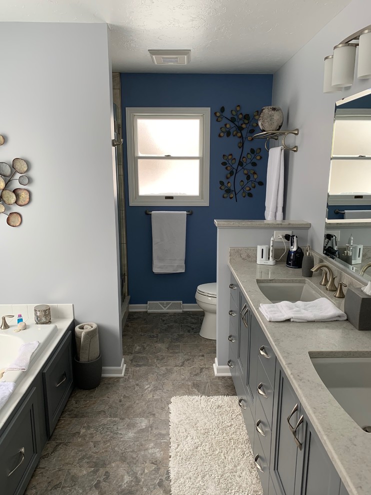 Cette photo montre une douche en alcôve principale de taille moyenne avec un placard à porte shaker, des portes de placard grises, une baignoire posée, WC séparés, un carrelage beige, des carreaux de céramique, un mur gris, un sol en vinyl, un lavabo encastré, un plan de toilette en quartz modifié, un sol gris, une cabine de douche à porte battante et un plan de toilette gris.