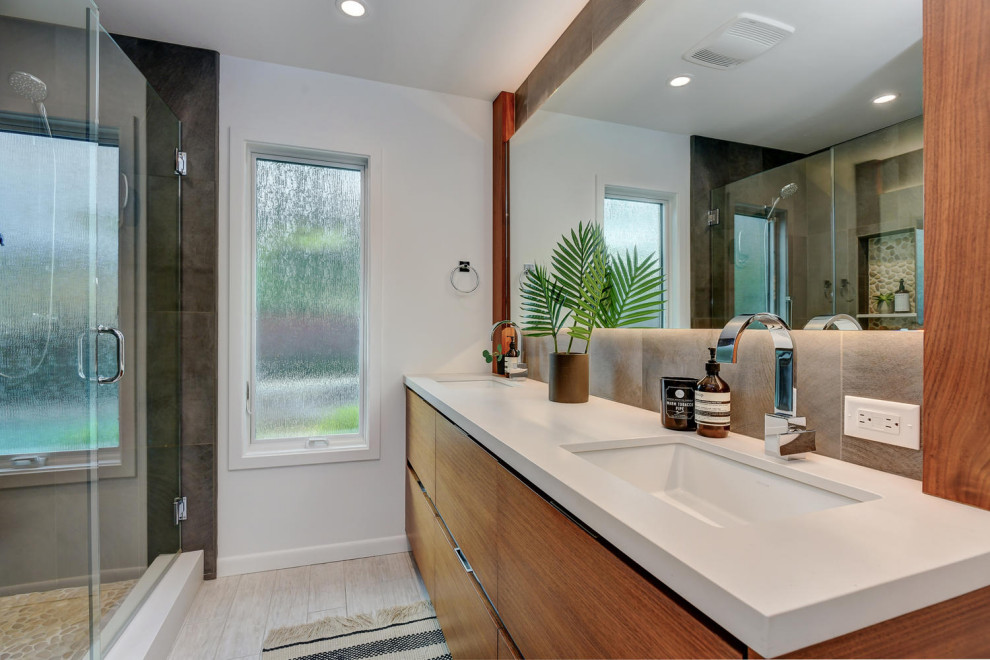 This is an example of a medium sized modern ensuite bathroom in San Francisco with shaker cabinets, medium wood cabinets, a corner shower, a one-piece toilet, white tiles, white walls, medium hardwood flooring, a submerged sink, granite worktops, brown floors, a hinged door and white worktops.