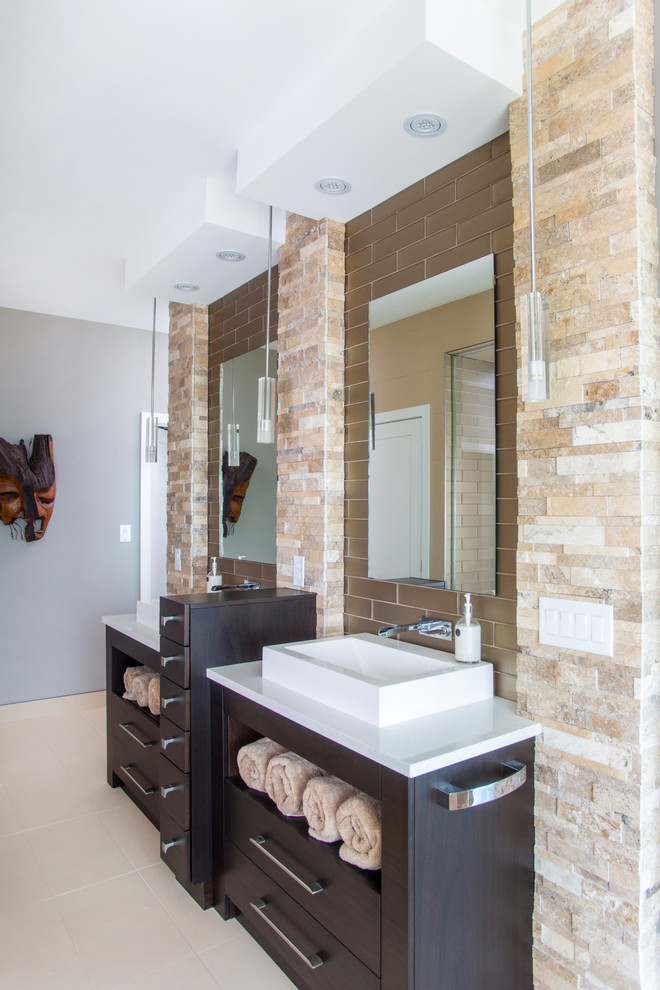 Inspiration for a large industrial ensuite bathroom in Toronto with flat-panel cabinets, brown cabinets, a built-in bath, an alcove shower, beige tiles, brown tiles, stone tiles, beige walls, porcelain flooring, a trough sink, engineered stone worktops, beige floors and a hinged door.