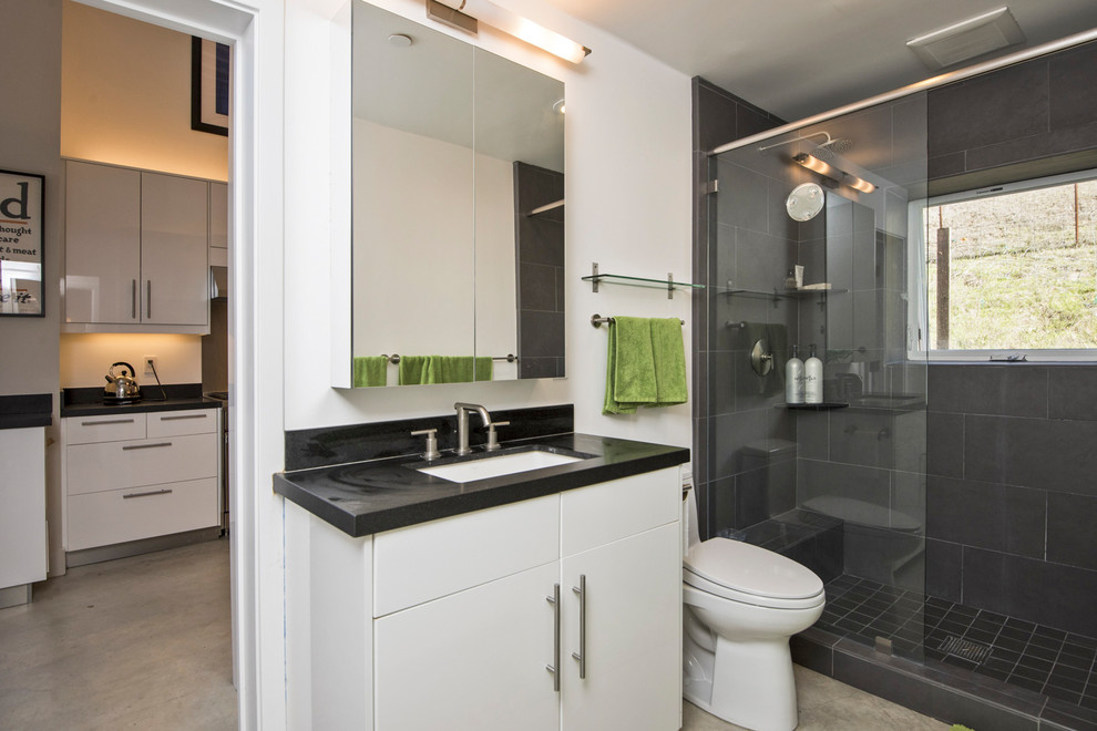 Idee per una piccola stanza da bagno padronale minimal con ante lisce, ante bianche, WC monopezzo, pareti gialle, pavimento in cemento, lavabo sottopiano, top in granito, pavimento grigio e doccia aperta