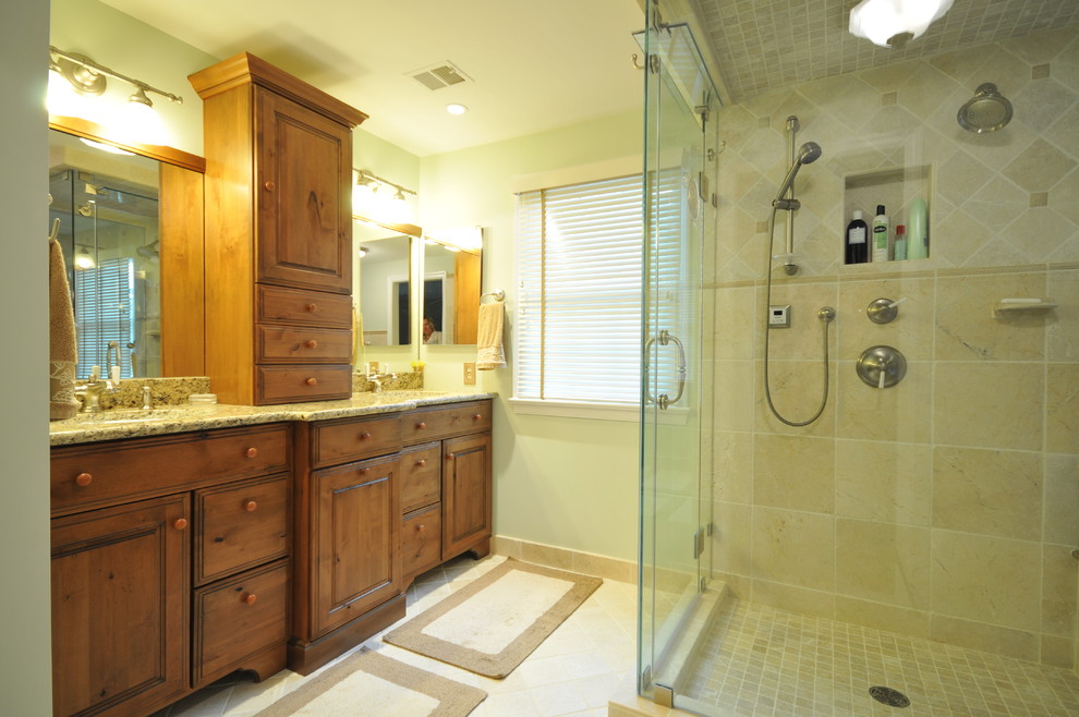 Immagine di una stanza da bagno padronale tradizionale con lavabo sottopiano, ante con bugna sagomata, ante in legno scuro, top in granito, piastrelle beige, piastrelle in pietra, pareti verdi e pavimento in travertino