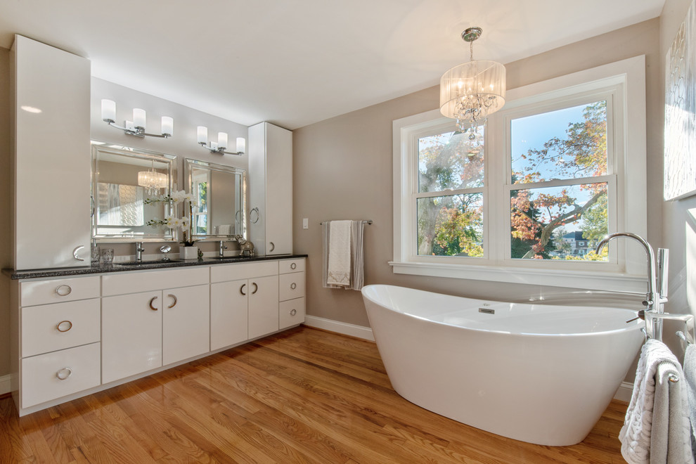 Inspiration for a large 1960s master multicolored tile and porcelain tile medium tone wood floor and brown floor bathroom remodel in Wilmington with flat-panel cabinets, white cabinets, a two-piece toilet, beige walls, an undermount sink, quartz countertops, a hinged shower door and gray countertops