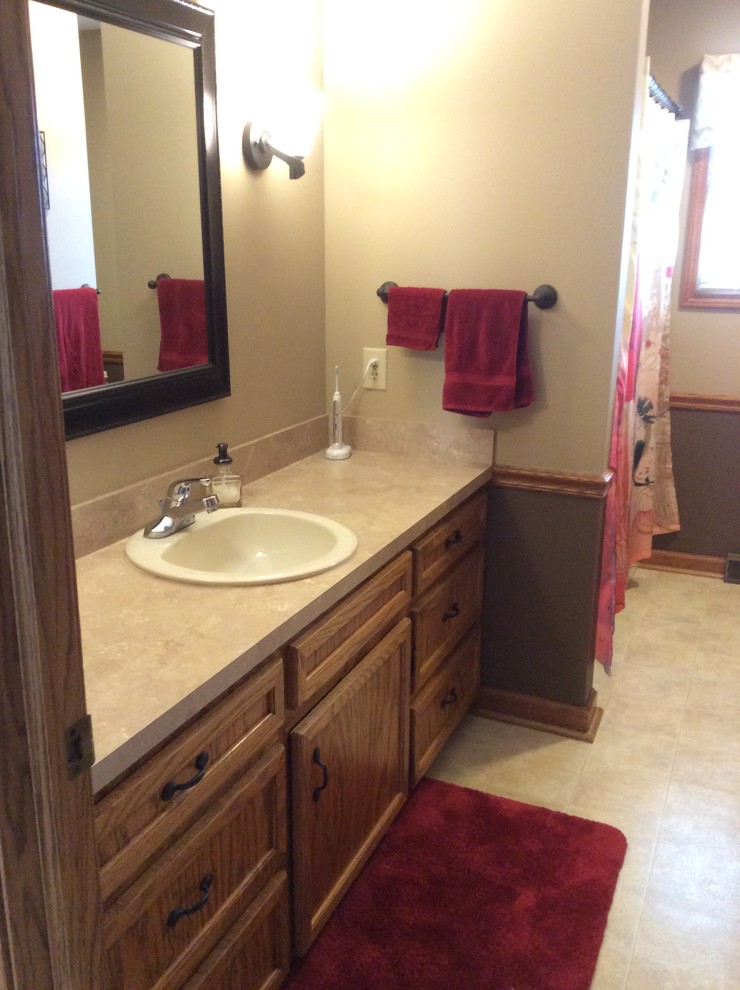 This is an example of a medium sized classic ensuite bathroom in Grand Rapids with shaker cabinets, medium wood cabinets, a shower/bath combination, vinyl flooring, a built-in sink and laminate worktops.