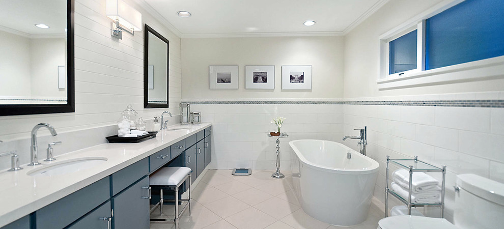 Cette image montre une salle de bain design avec une baignoire indépendante et des portes de placard bleues.