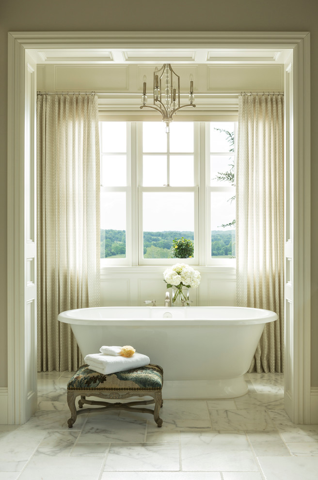 Klassisk inredning av ett stort en-suite badrum, med ett fristående badkar, beige väggar, luckor med upphöjd panel, vita skåp, en dusch i en alkov, en toalettstol med separat cisternkåpa, marmorgolv, ett undermonterad handfat och granitbänkskiva