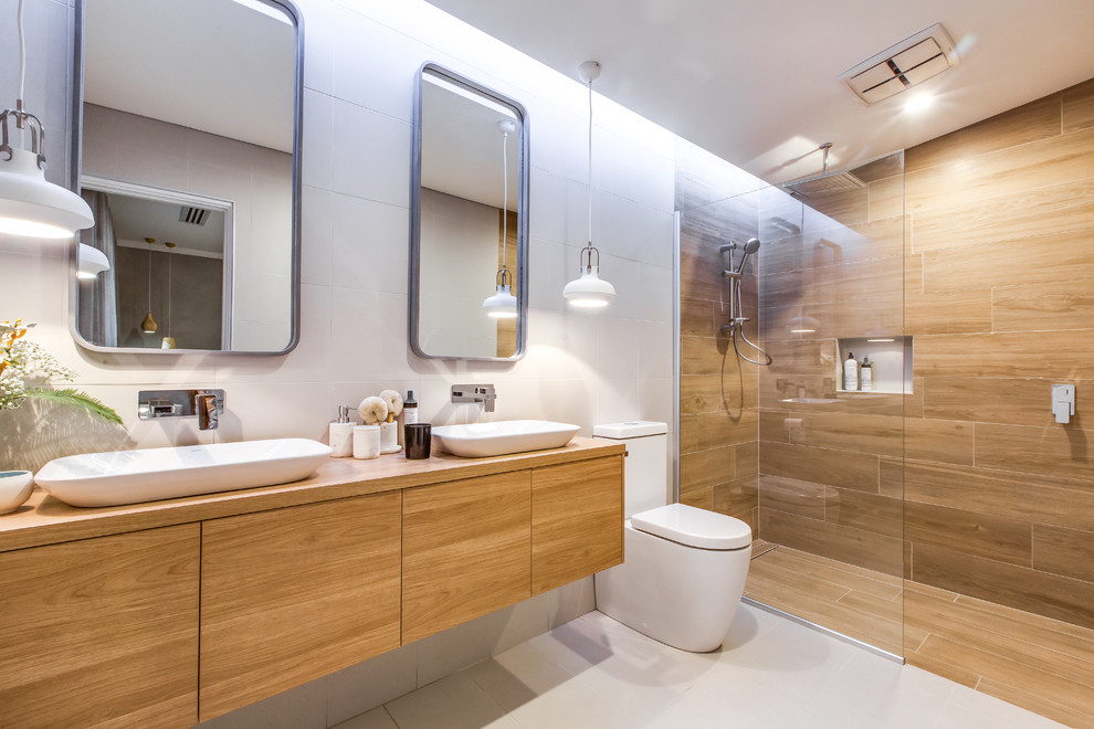 Example of a mid-sized trendy master white tile beige floor bathroom design in Perth with light wood cabinets, a one-piece toilet, wood countertops, flat-panel cabinets, white walls, a vessel sink and brown countertops
