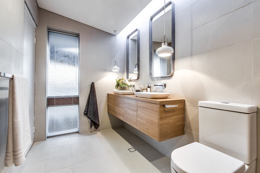 Immagine di una stanza da bagno minimalista di medie dimensioni con ante in legno chiaro, WC monopezzo, piastrelle bianche e top in legno
