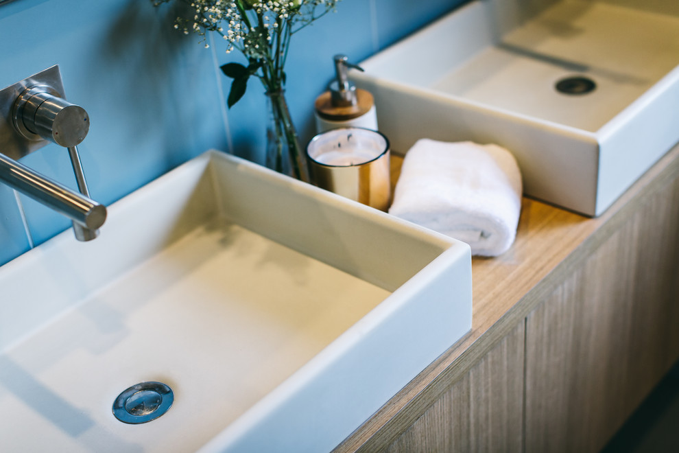 Стильный дизайн: ванная комната в стиле модернизм с светлыми деревянными фасадами, синей плиткой и столешницей из дерева - последний тренд