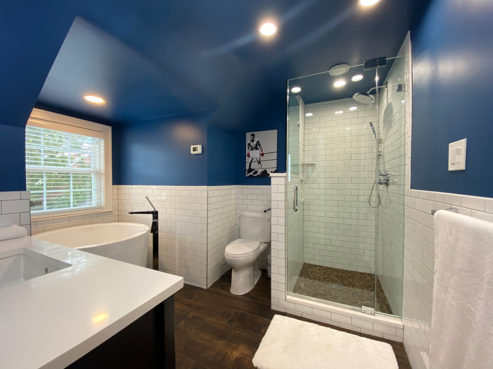 Photo of a medium sized classic family bathroom in New York with open cabinets, brown cabinets, a freestanding bath, a corner shower, a two-piece toilet, white tiles, ceramic tiles, blue walls, porcelain flooring, a submerged sink, engineered stone worktops, brown floors, a hinged door and white worktops.