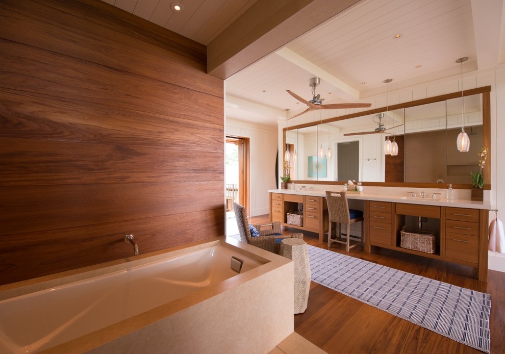 Design ideas for a large world-inspired ensuite bathroom in Hawaii with flat-panel cabinets, medium wood cabinets, a submerged bath, white walls, medium hardwood flooring, an integrated sink, engineered stone worktops, an alcove shower, a two-piece toilet, white tiles, stone slabs, brown floors and a hinged door.