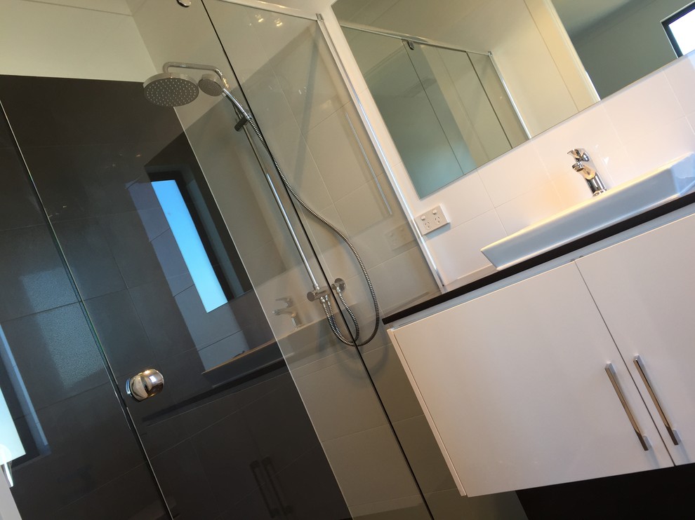 Ispirazione per una stanza da bagno design con ante lisce, ante bianche, doccia alcova, lavabo integrato, top in superficie solida e porta doccia a battente