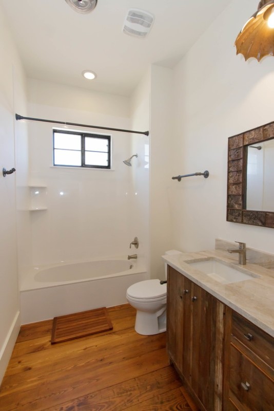 Medium sized rustic shower room bathroom in Austin with flat-panel cabinets, dark wood cabinets, an alcove bath, a shower/bath combination, a two-piece toilet, white tiles, porcelain tiles, white walls, dark hardwood flooring, a submerged sink, marble worktops, brown floors and a shower curtain.