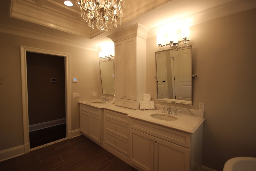 Стильный дизайн: большая главная ванная комната в стиле неоклассика (современная классика) с фасадами с утопленной филенкой, белыми фасадами, угловым душем, унитазом-моноблоком, бежевыми стенами, полом из керамогранита, врезной раковиной, мраморной столешницей и отдельно стоящей ванной - последний тренд