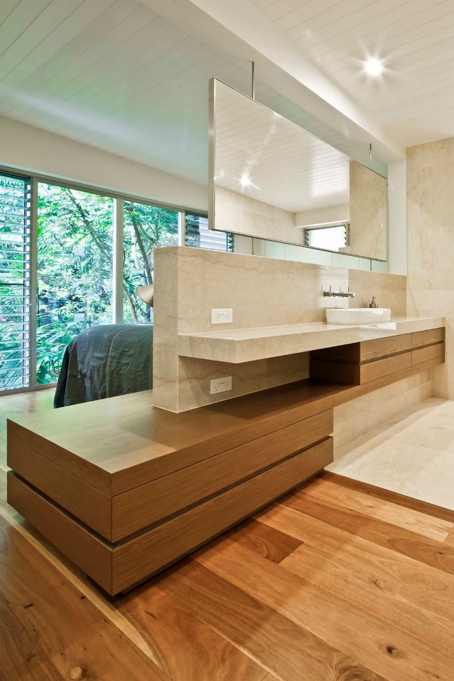 Cette image montre une salle de bain principale minimaliste en bois brun de taille moyenne avec un placard à porte plane, un carrelage beige, des dalles de pierre, un mur beige, un sol en marbre, un lavabo intégré et un plan de toilette en marbre.