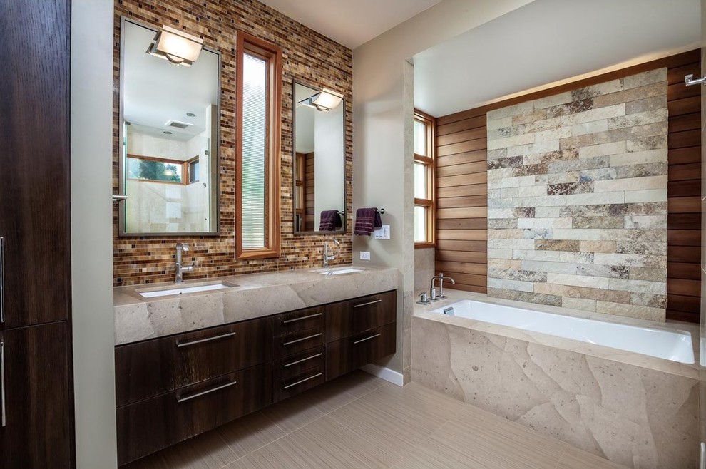 Idee per una stanza da bagno design con ante lisce, ante in legno bruno, vasca sottopiano, piastrelle multicolore, piastrelle in pietra, pareti grigie e lavabo sottopiano