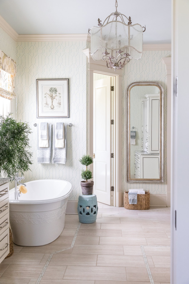 Imagen de cuarto de baño clásico con puertas de armario blancas, bañera exenta, paredes blancas, suelo beige, encimeras grises y papel pintado