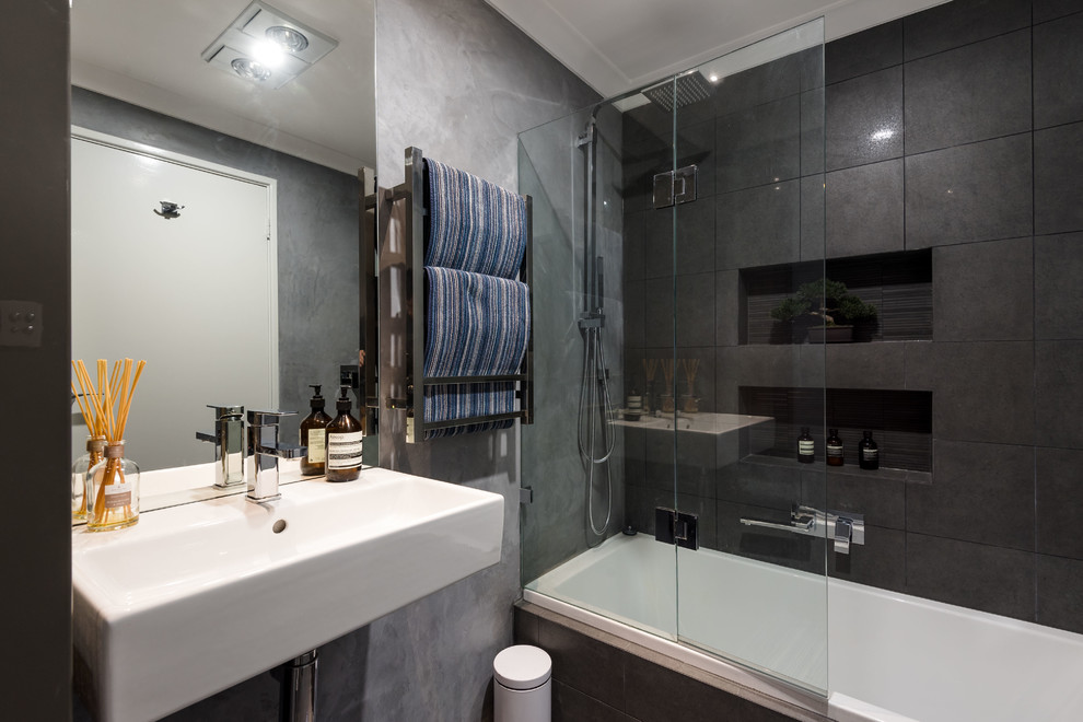 Idee per una stanza da bagno minimal con vasca ad alcova, vasca/doccia, piastrelle nere, pareti nere, lavabo sospeso e doccia aperta
