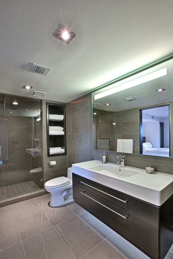 Immagine di una stanza da bagno design di medie dimensioni con ante lisce, piastrelle marroni, piastrelle in gres porcellanato, lavabo integrato e doccia ad angolo