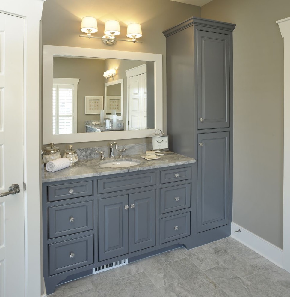 Cette photo montre une salle de bain principale bord de mer avec un placard avec porte à panneau surélevé, des portes de placard bleues, un mur gris, un lavabo encastré, un sol gris, meuble double vasque et meuble-lavabo encastré.