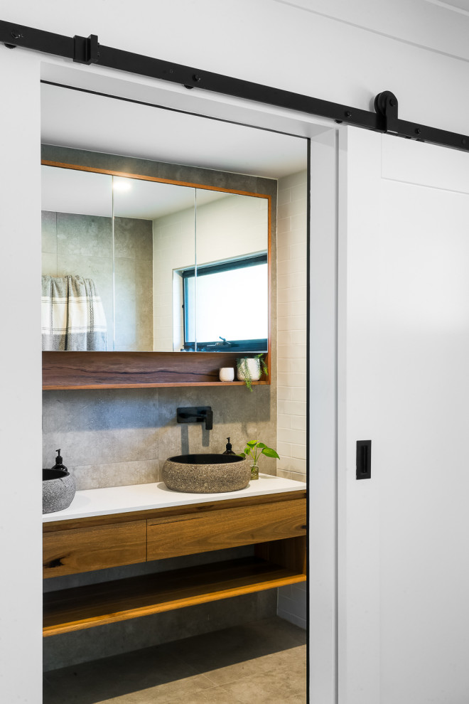 Design ideas for a medium sized contemporary shower room bathroom in Brisbane with flat-panel cabinets, medium wood cabinets, grey tiles, white walls, a vessel sink, grey floors, white worktops, double sinks and a floating vanity unit.