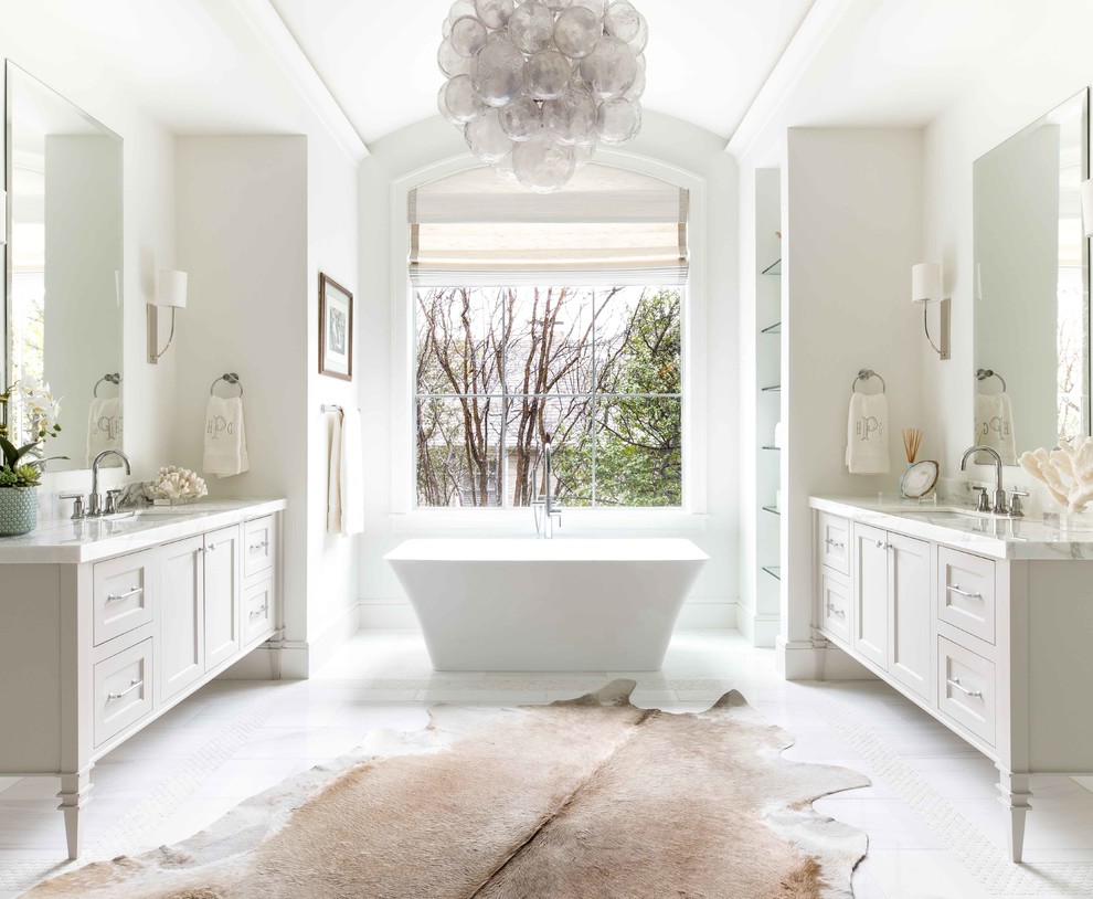 Exemple d'une salle de bain principale bord de mer avec des portes de placard grises, une baignoire indépendante, un mur blanc, un lavabo encastré, un sol blanc, un plan de toilette blanc et un placard à porte shaker.