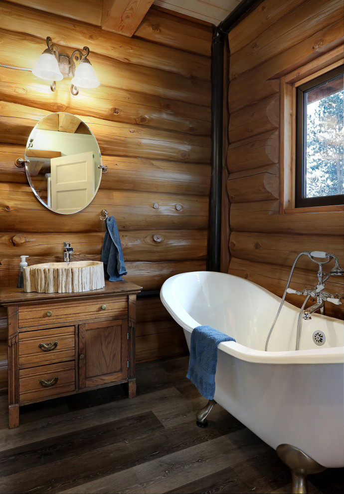 Foto på ett mellanstort rustikt brun badrum med dusch, med möbel-liknande, skåp i mellenmörkt trä, ett badkar med tassar, en dusch i en alkov, en toalettstol med hel cisternkåpa, bruna väggar, mellanmörkt trägolv, ett fristående handfat, grått golv och dusch med gångjärnsdörr