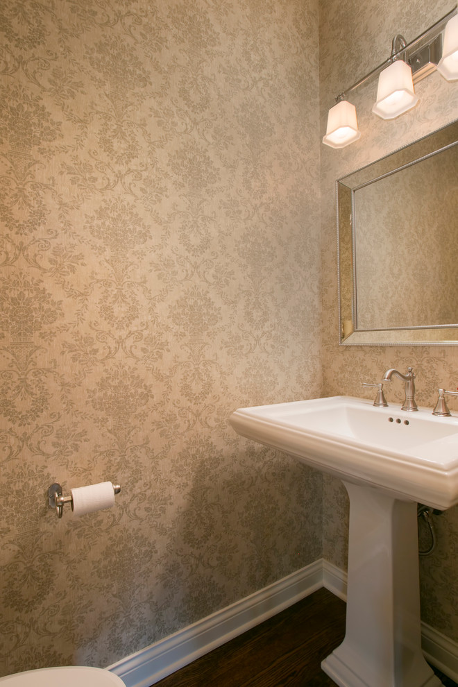 Diseño de cuarto de baño clásico pequeño con sanitario de dos piezas, paredes beige, suelo de madera oscura, aseo y ducha, lavabo con pedestal y suelo marrón