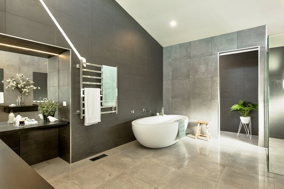 Стильный дизайн: огромная главная ванная комната в современном стиле с отдельно стоящей ванной, двойным душем, раздельным унитазом, серой плиткой, керамогранитной плиткой, белыми стенами, полом из керамогранита, настольной раковиной, столешницей из ламината, серым полом, открытым душем и черной столешницей - последний тренд